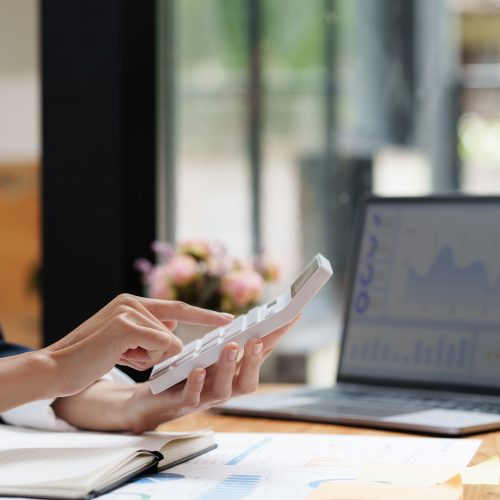 Asian Business woman writing saving account balance with working at home, account and saving concept